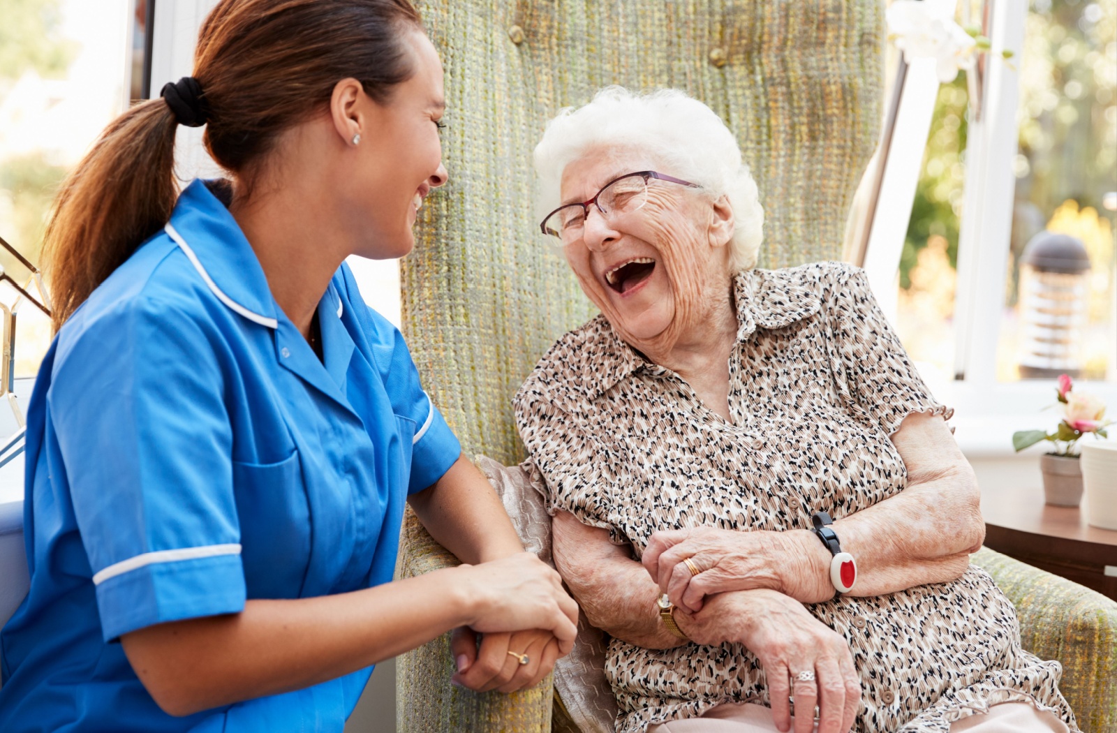 A senior and caregiver enjoying a joyful moment together outside.
