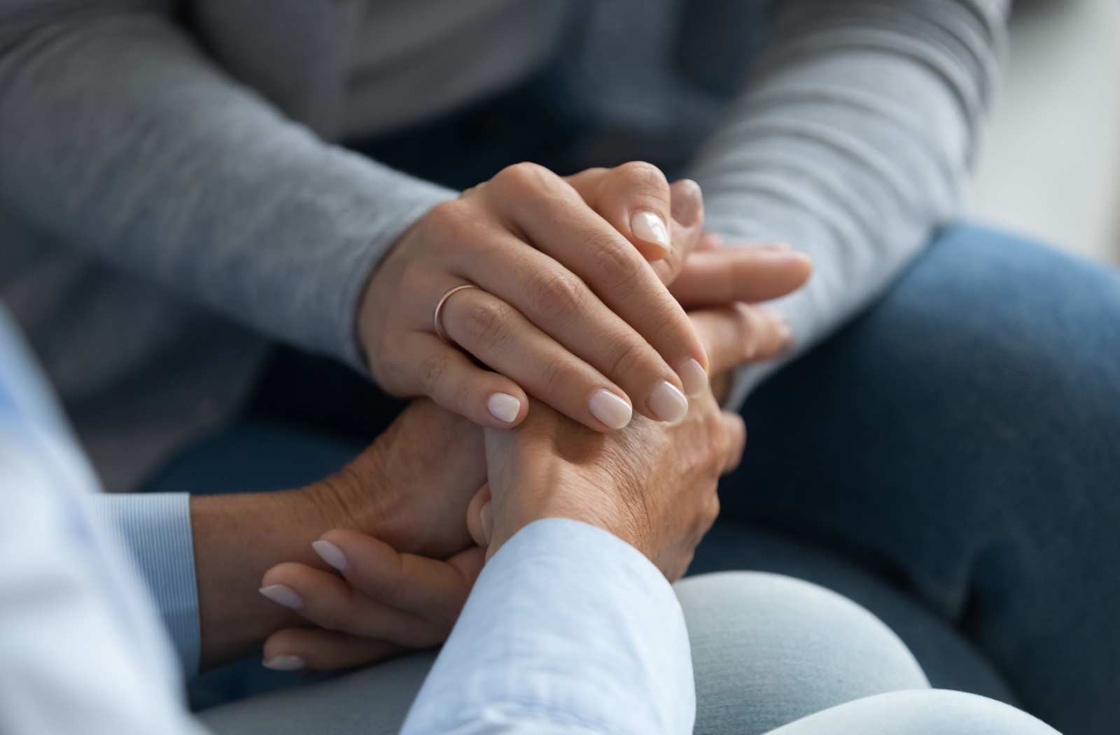 A close-up image of a pair of hands as an adult child comforts their older parent about needing help.