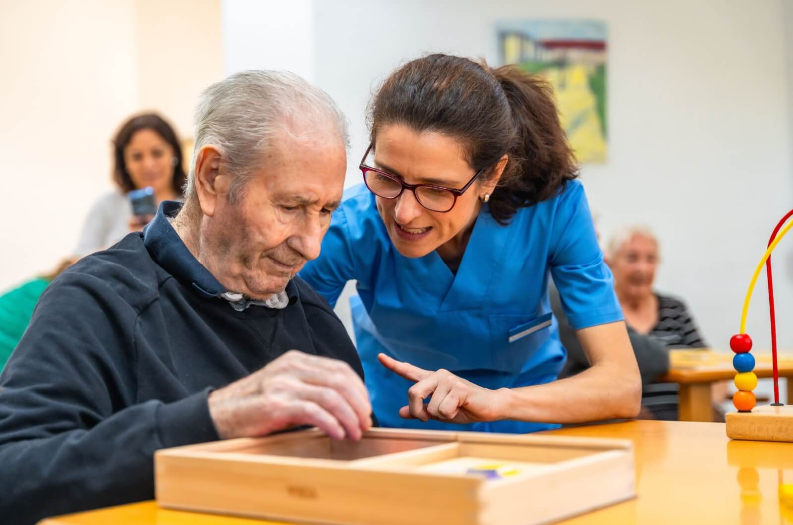 A staff member in memory care assisting an older adult with an activity.