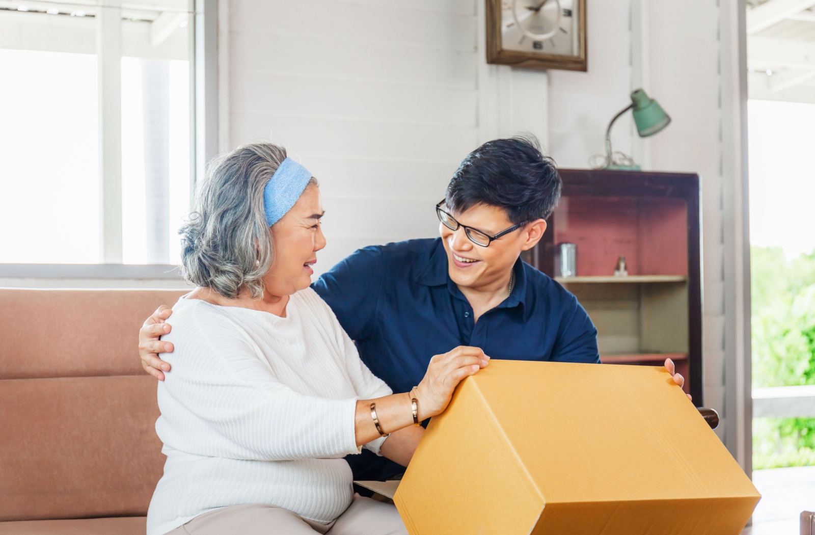 An adult son helps his mother pack a box in preparation for the move to assisted living.