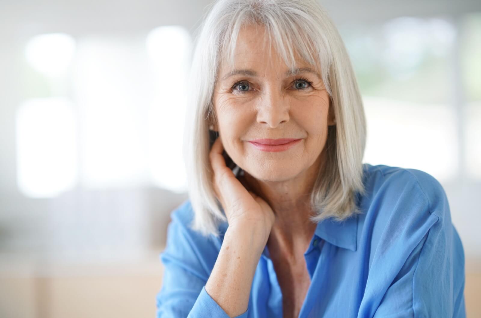 A smiling older woman in a blue shirt with a shoulder-length bob hairstyle.