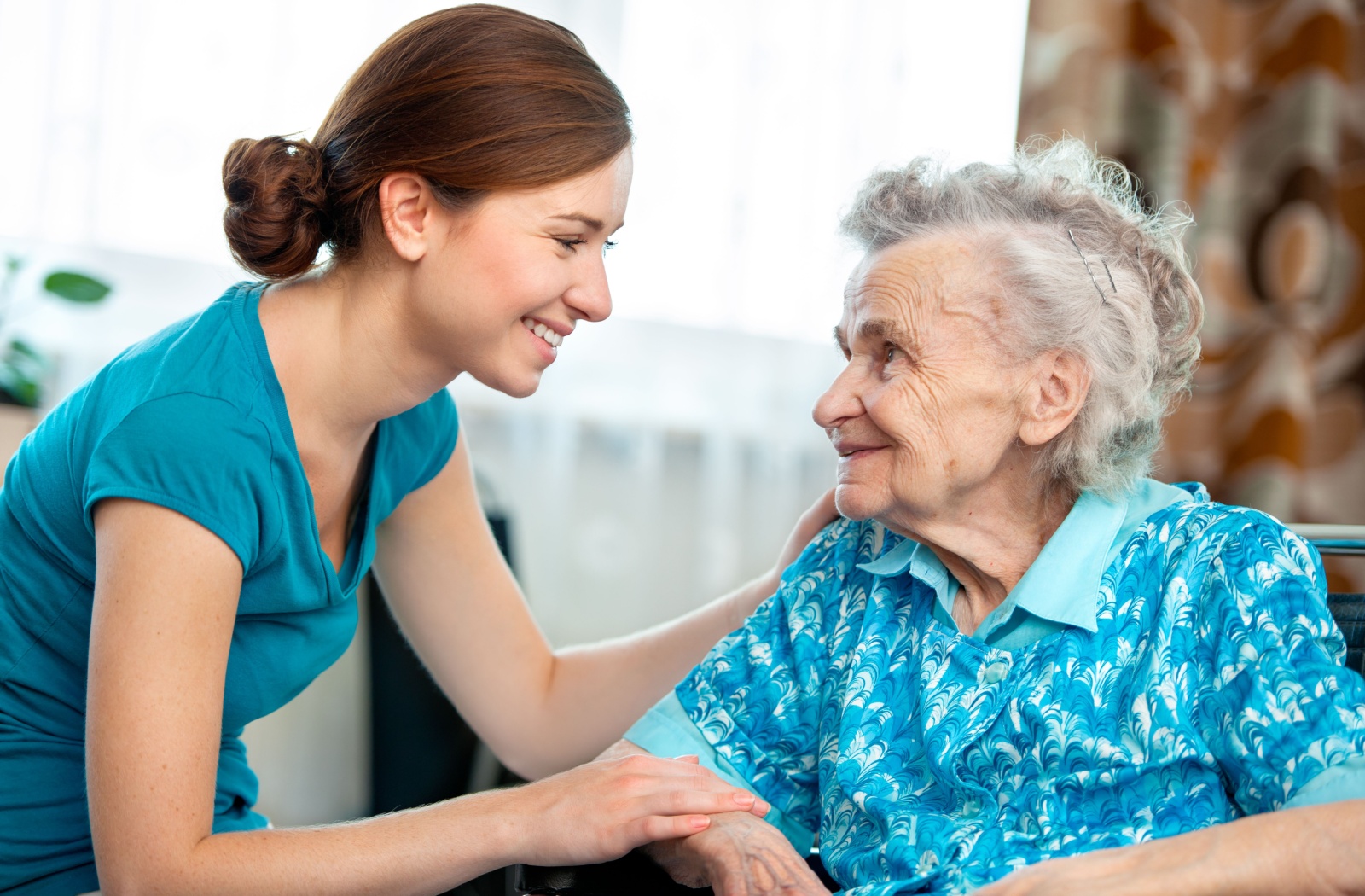 A smiling caregiver checks in with a senior who is enjoying their short-term stay in the assisted living community.
