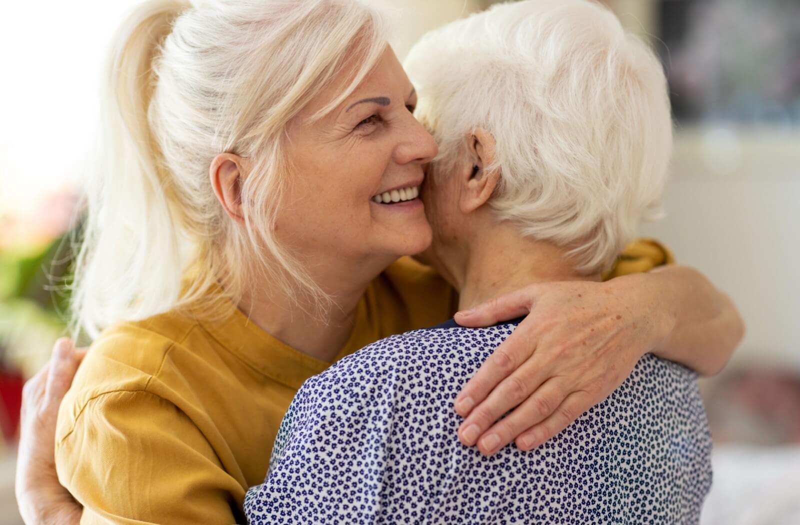 An adult embraces their senior parent with dementia, giving them physical reassurance of their love and support